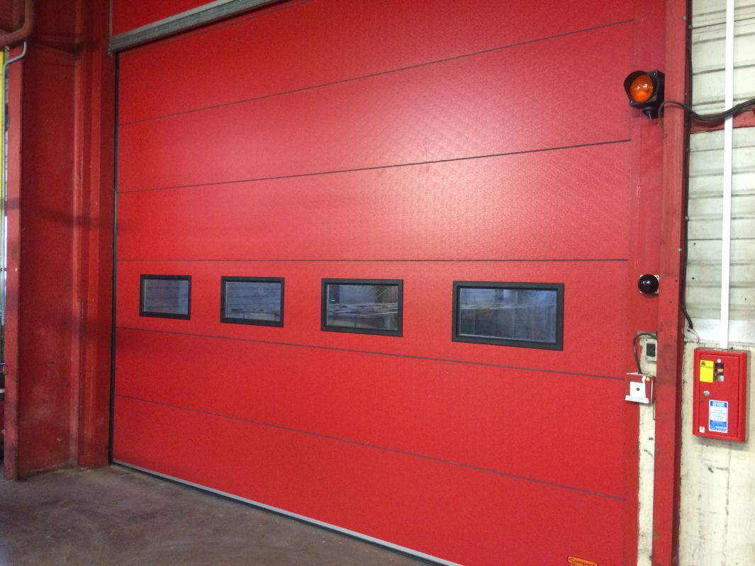 Installation de portes sectionnelles empilables sur Calais de couleur rouge. 