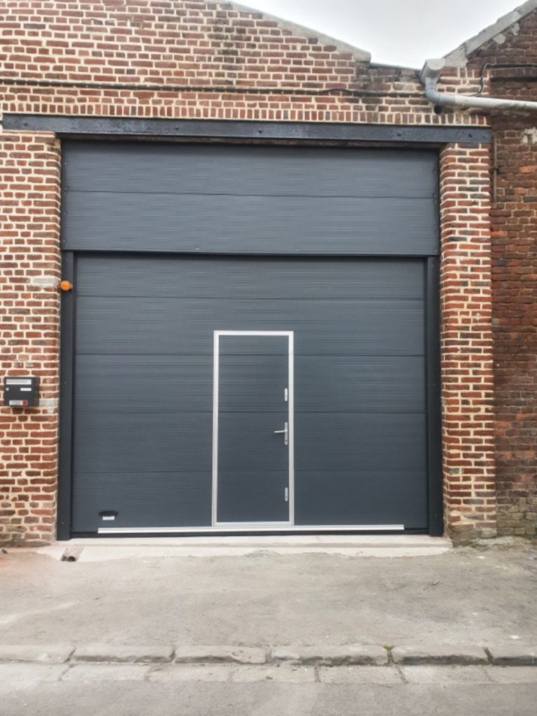 Installation d'une porte sectionnelle avec imposte et portillon vue de l'extérieur. 